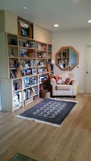 Cozy living room with a central seating area, ornate bookshelf, and plush rug.