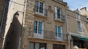 Un immeuble à plusieurs étages, doté d’une façade en pierre, de balcons avec des garde-corps en fer forgé et d’une entrée au niveau du sol avec une porte.