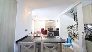 Zona pranzo con tavolo e sedie, una sedia rossa, una sedia blu e una scala con ringhiera decorativa.