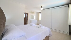 Una camera da letto con un letto, una cassettiera, uno specchio e un armadio.