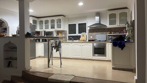 A spacious kitchen with white cabinetry, a central island, and a built-in oven. - VILLA LES PALMIERS /300M2/15 PERS/PISCINE/7 CH/6 SDB/GARAGE/EXCEPTIONAL VIEWS (Aourir)
