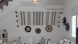 A modern living room with a white sofa set, a coffee table, and decorative wall hangings. - VILLA LES PALMIERS /300M2/15 PERS/PISCINE/7 CH/6 SDB/GARAGE/EXCEPTIONAL VIEWS (Aourir)
