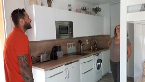 Una cocina moderna con armarios blancos, microondas, tostadora y lavadora.