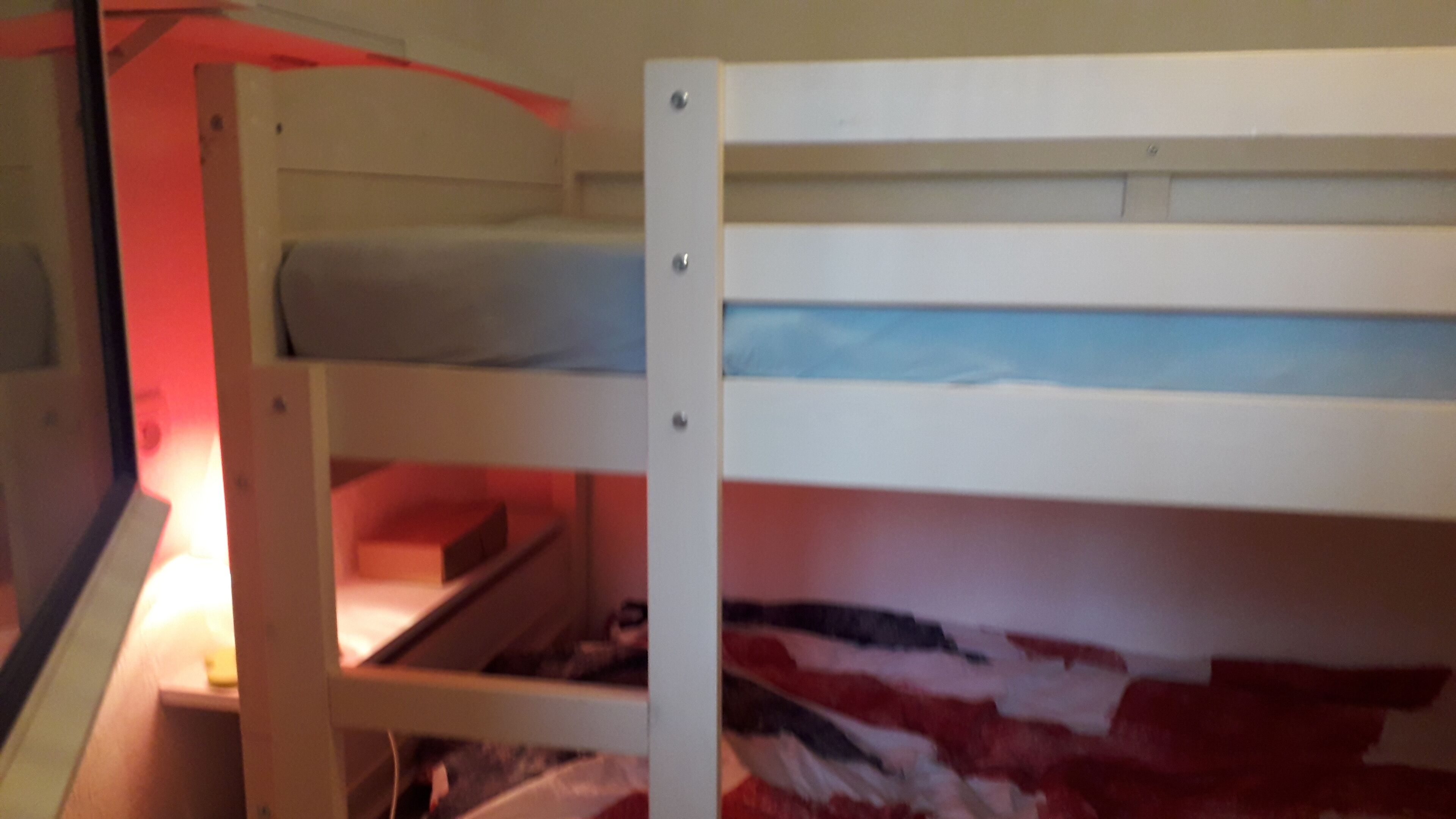 A bunk bed with a mattress on the top bunk and a lower bunk with a storage compartment.