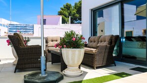 Un espace extérieur aménagé avec des meubles en osier et un grand bac à fleurs.
