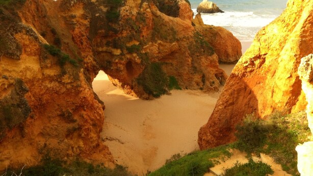 Un paysage côtier caractérisé par des formations rocheuses et une plage de sable.
