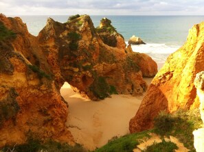 Un paysage côtier caractérisé par des formations rocheuses et une plage de sable.