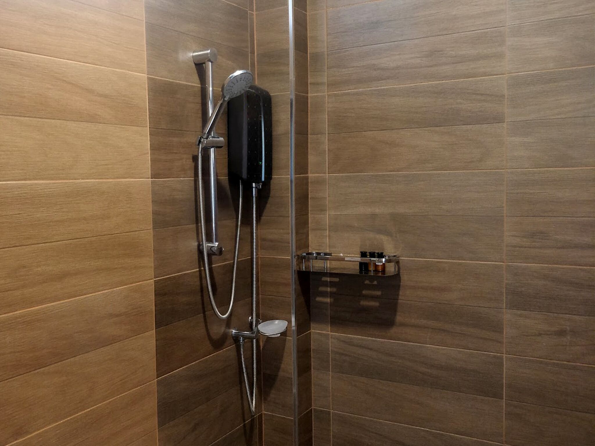 A shower with a handheld showerhead and a wall-mounted control panel.