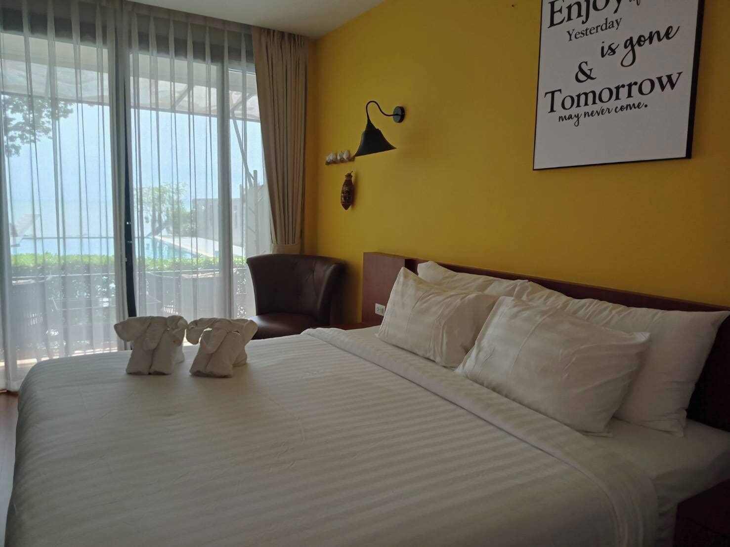 Een hotelkamer met een bed, een stoel en uitzicht op de omgeving door grote ramen.