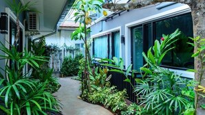 A narrow pathway flanked by lush green plants and a building with large windows. - Blue Orchid Beach Krabi (Krabi)