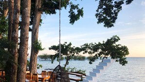 A wooden deck with outdoor seating, a hanging chair, and a staircase leading to a white structure by a body of water. - Blue Orchid Beach Krabi (Krabi)