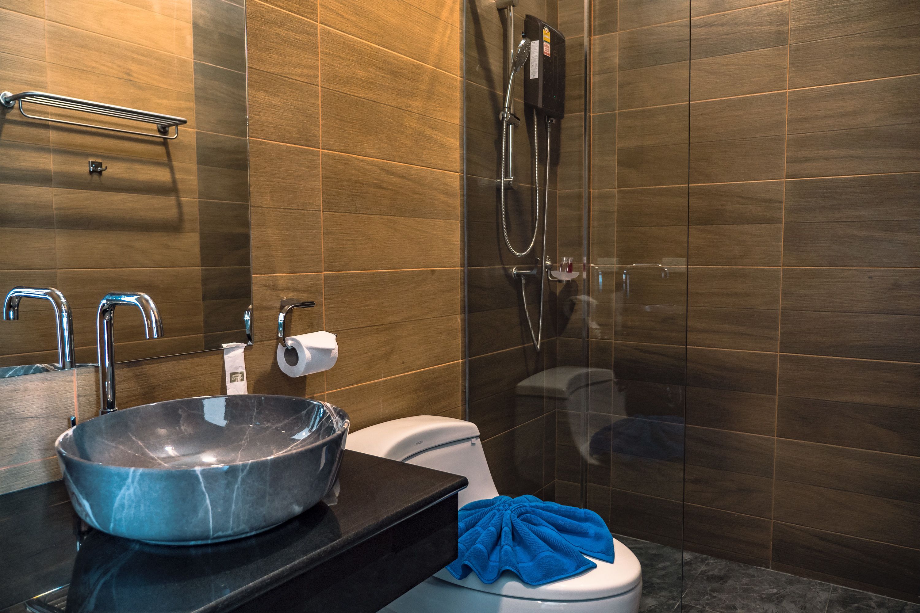 Un baño moderno con un lavamanos grande tipo recipiente, un inodoro y una ducha con cerramiento de vidrio.