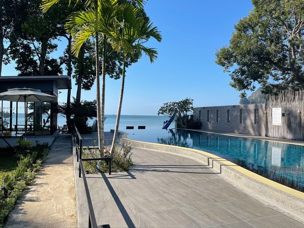 A pool area with a clear view of the sea, surrounded by palm trees and a covered seating area. - Blue Orchid Beach Krabi (Krabi)