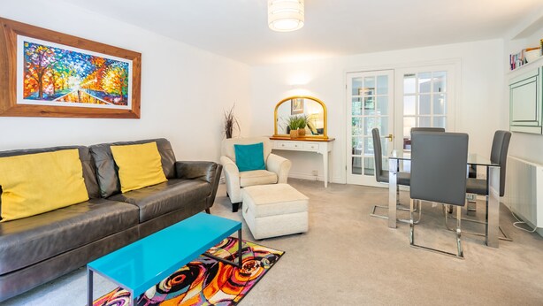 Un salon comprenant un canapé, une table basse, un coin repas avec des chaises, un miroir et un tableau accroché au mur.