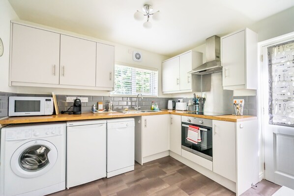 A compact kitchen with white cabinets, a microwave, a dishwasher, and an oven.