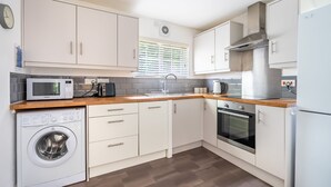 Une cuisine moderne avec des meubles blancs, un lave-linge, un four à micro-ondes, une cuisinière et un réfrigérateur.