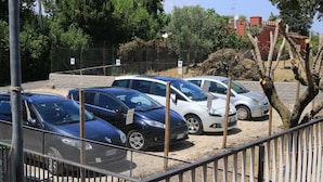 A parking area with several cars parked in a row, surrounded by a fence and trees. - La Casa dell'Orso (Ciampino)