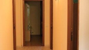 A narrow hallway with wooden doors on either side and a light fixture on the right wall. - La Casa dell'Orso (Ciampino)