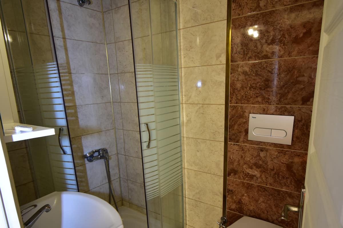 Casa de banho com cabine de duche de vidro, sanita e lavatório.