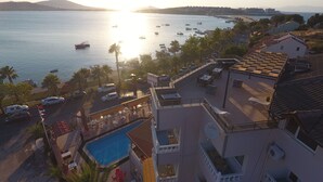 Un hotel frente al mar con piscina en la azotea y vistas al océano, además de un estacionamiento.