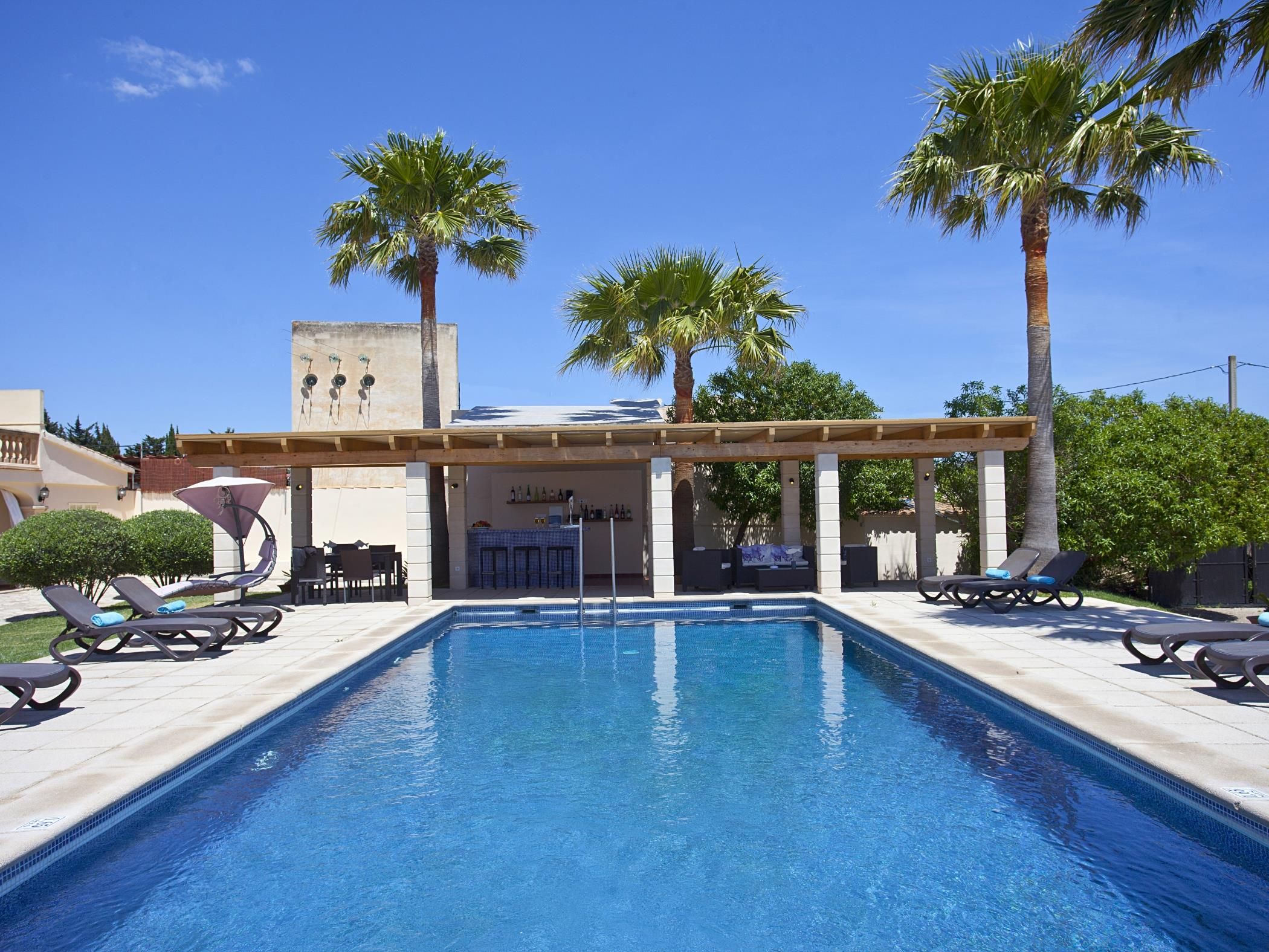 A swimming pool with lounge chairs and palm trees.