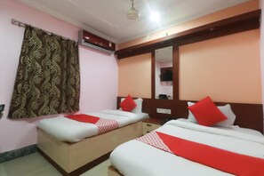 A hotel room with two beds, a mirror, a wardrobe, and a curtain.