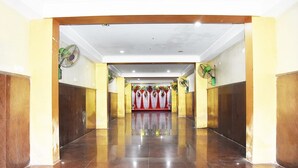 A hallway with a polished floor, flanked by wooden panels and two standing fans. - Hotel Nirmala Residency (Bhubaneshwar)