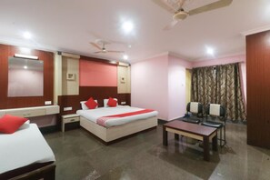 A hotel room with a bed, bedside tables, a desk, and a ceiling fan. - Hotel Nirmala Residency (Bhubaneshwar)