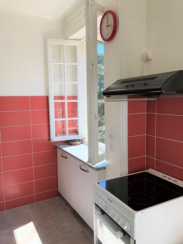 A kitchen with a window, a stove, and a clock on the wall. - Hossegor city center- Flat for 4 persons with view on the marine lake channel (SOORTS HOSSEGOR)