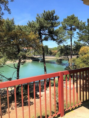 A view of a river with trees and a red railing in the foreground. - Hossegor city center- Flat for 4 persons with view on the marine lake channel (SOORTS HOSSEGOR)
