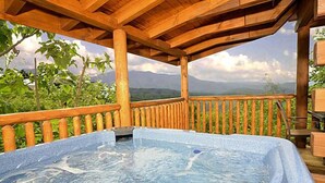 A hot tub on a wooden deck with a mountain view.