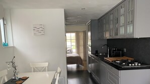 Une cuisine moderne avec un coin repas, comprenant une table et des chaises blanches, un plan de travail noir et des armoires grises.