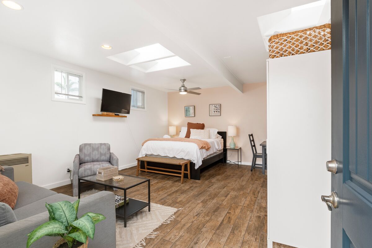Un dormitorio moderno con cama, mesitas de noche, televisor y ventilador de techo.