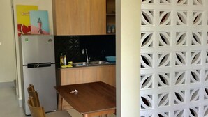 A modern kitchen with wooden cabinets, a built-in refrigerator, and a dining area with a wooden table and chairs.