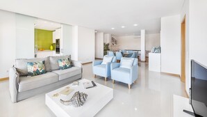 A modern living room with a grey sofa, a white coffee table, and light blue armchairs. - Flat Downtown OCV - 5min Beach (Albufeira)