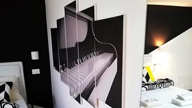 Ein modernes Hotelzimmer mit Bett, Schreibtisch und einem großen, abstrakten Gemälde an der Wand.
