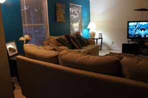 Relax in this inviting living room with a sofa, TV, and cozy reading nook.