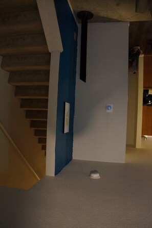 Stairs lead upwards between blue and white walls, with a piece of furniture at the base.