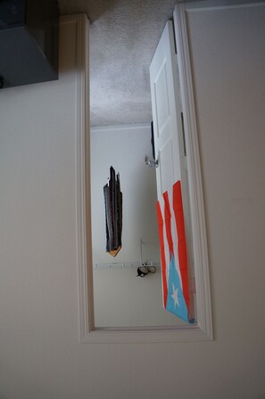 Enter a simple, functional space with a door leading to a room featuring a small shelf.