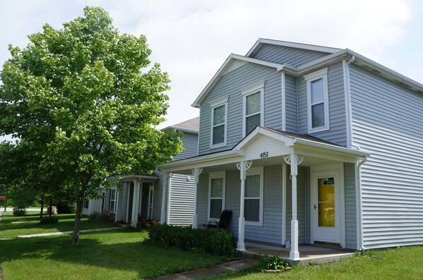 Two-story house with a well-maintained lawn and a shaded front porch.