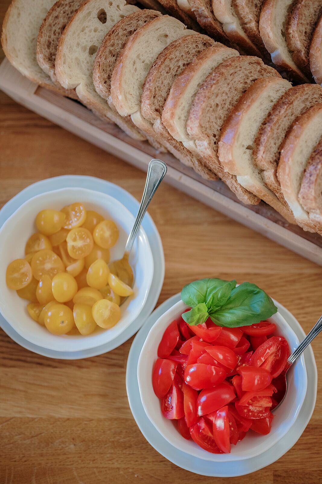 Pan en rodajas, tomates cherry y tomates cherry amarillos sobre una mesa de madera.