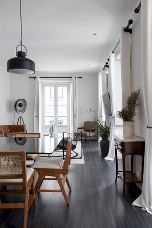 A modern living room with a dining area, featuring a large window, a sofa, a coffee table, and a TV. - Master Deco Gem in Bairro Alto (Lisboa)