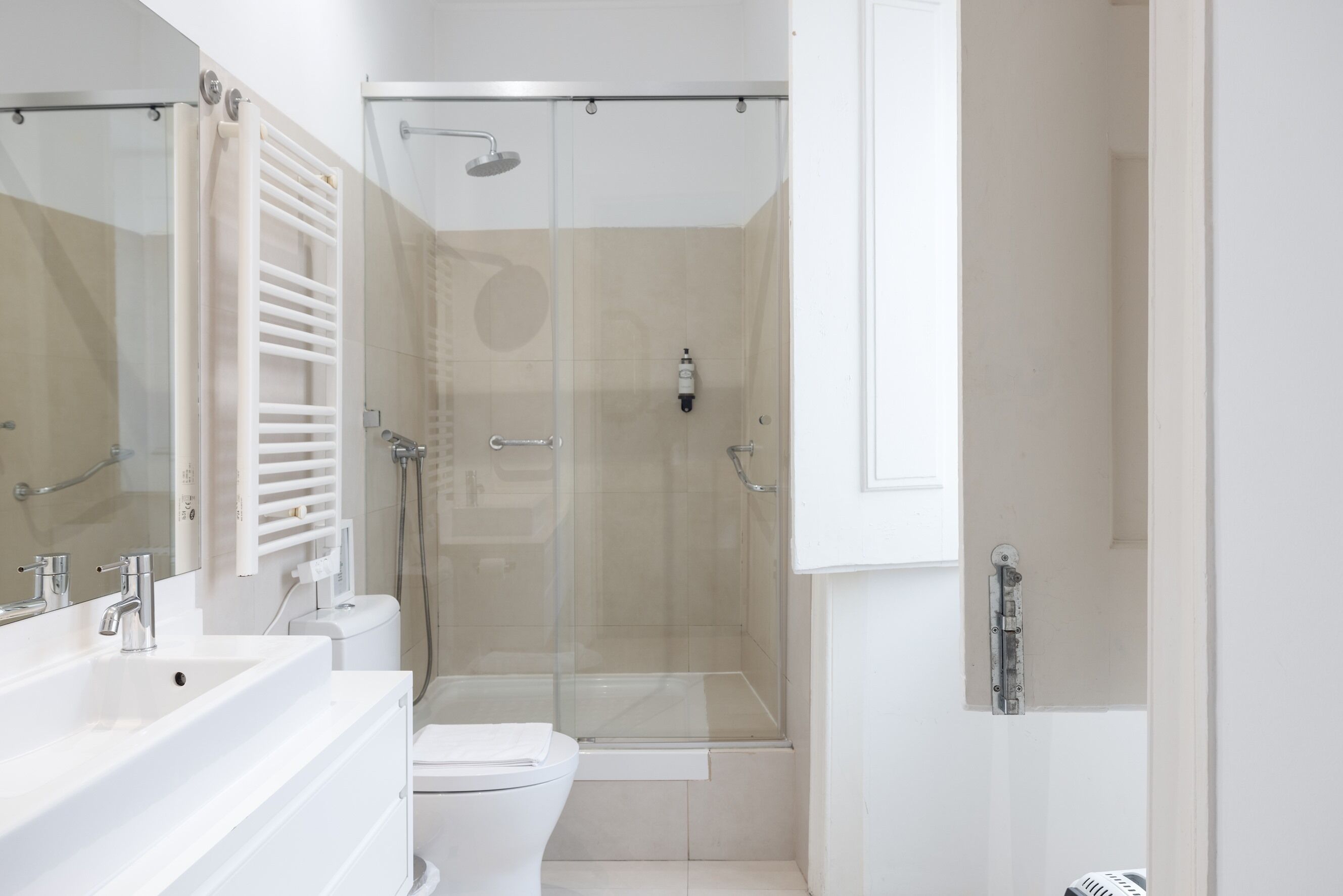 A modern bathroom with a glass-enclosed shower, a white sink, and a toilet.