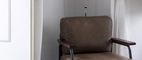 A modern room with a brown leather chair, a floor lamp, and a white rug.