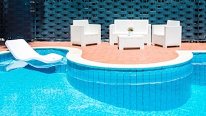 A swimming pool with white lounge chairs and a small table with a flower vase. - B&B Villa Liberty sul Mare - Camera Cobalto by Wonderful Italy (Palermo)