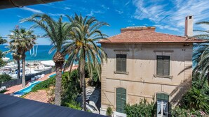 A coastal building with a red-tiled roof, a swimming pool, and palm trees. - B&B Villa Liberty sul Mare - Camera Cobalto by Wonderful Italy (Palermo)