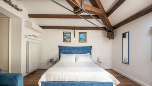 A bedroom with a large bed, wooden beams, white walls, and a blue headboard. - B&B Villa Liberty sul Mare - Camera Cobalto by Wonderful Italy (Palermo)