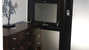 Una habitación con un escritorio de madera oscura, un árbol de metal decorativo y un ventanal con vidrio esmerilado.