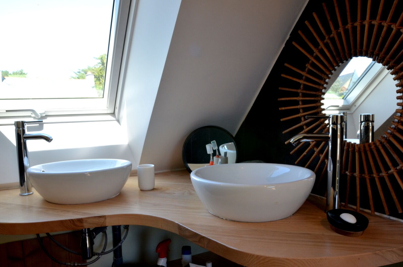 A modern bathroom with two white sinks, a mirror, and a wooden vanity.