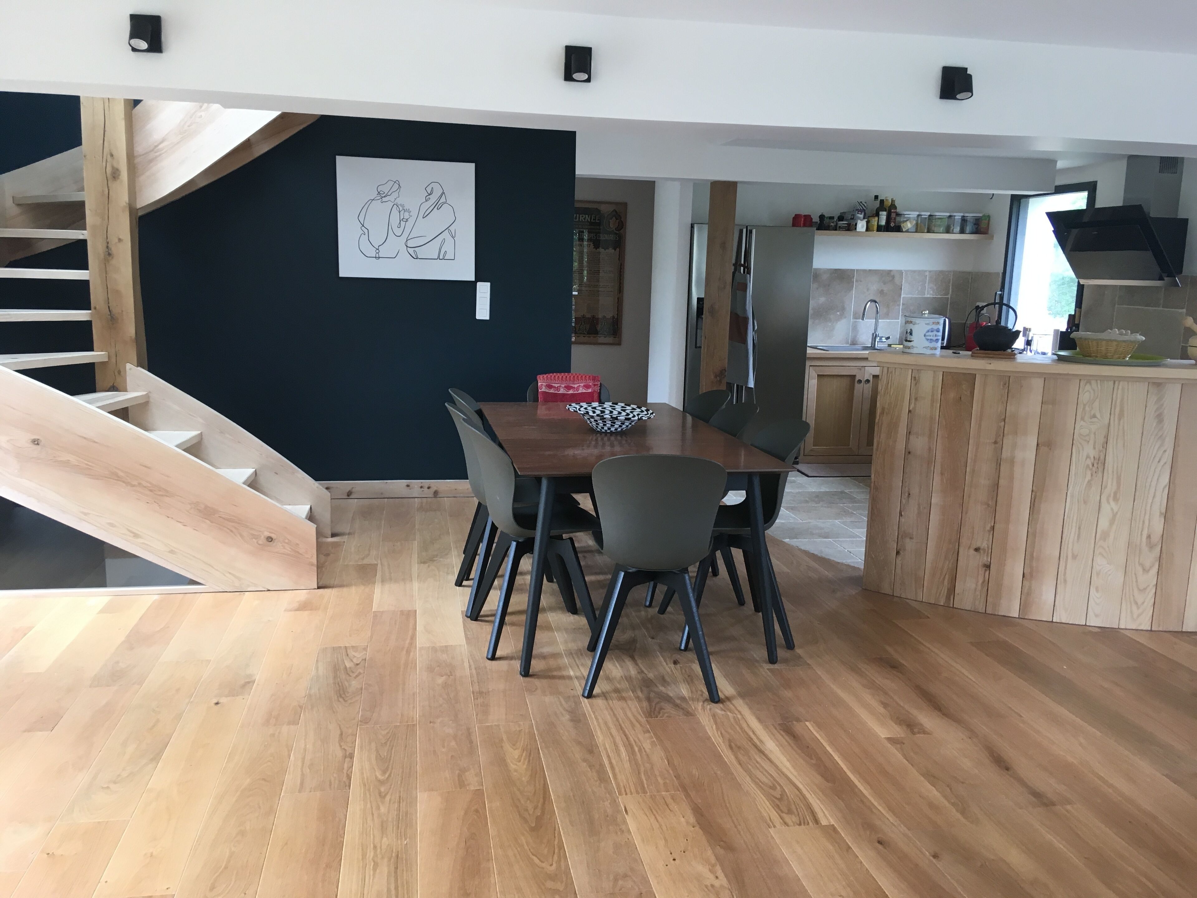 A modern kitchen with wooden cabinets, a built-in oven, and a dining area with a wooden table and chairs.
